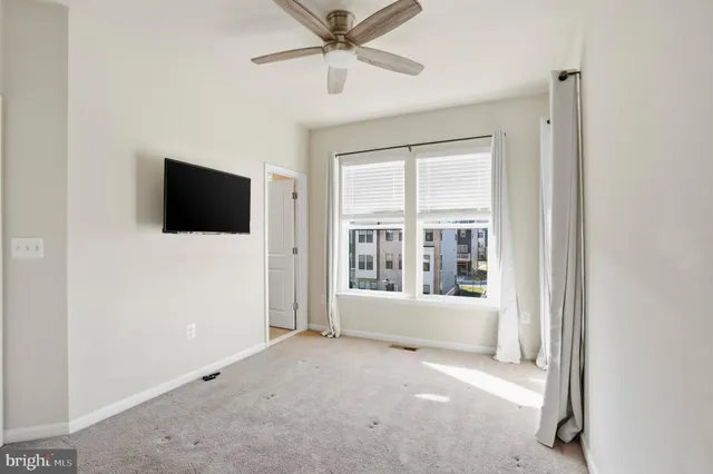 a view of a room with a ceiling fan and windows