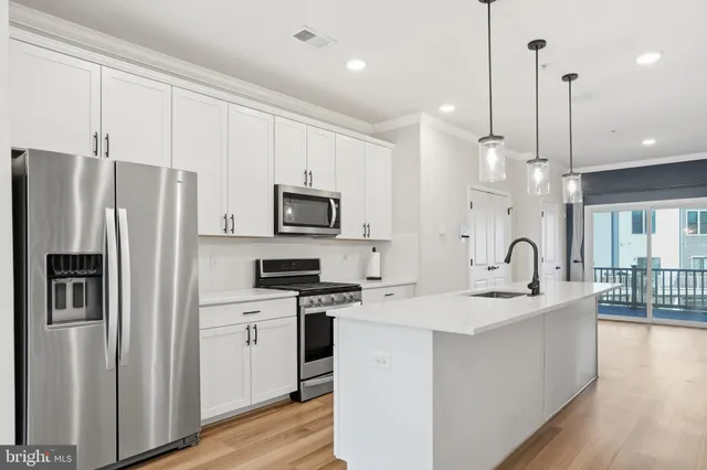 a kitchen with stainless steel appliances kitchen island a white cabinets a sink a stove and a refrigerator