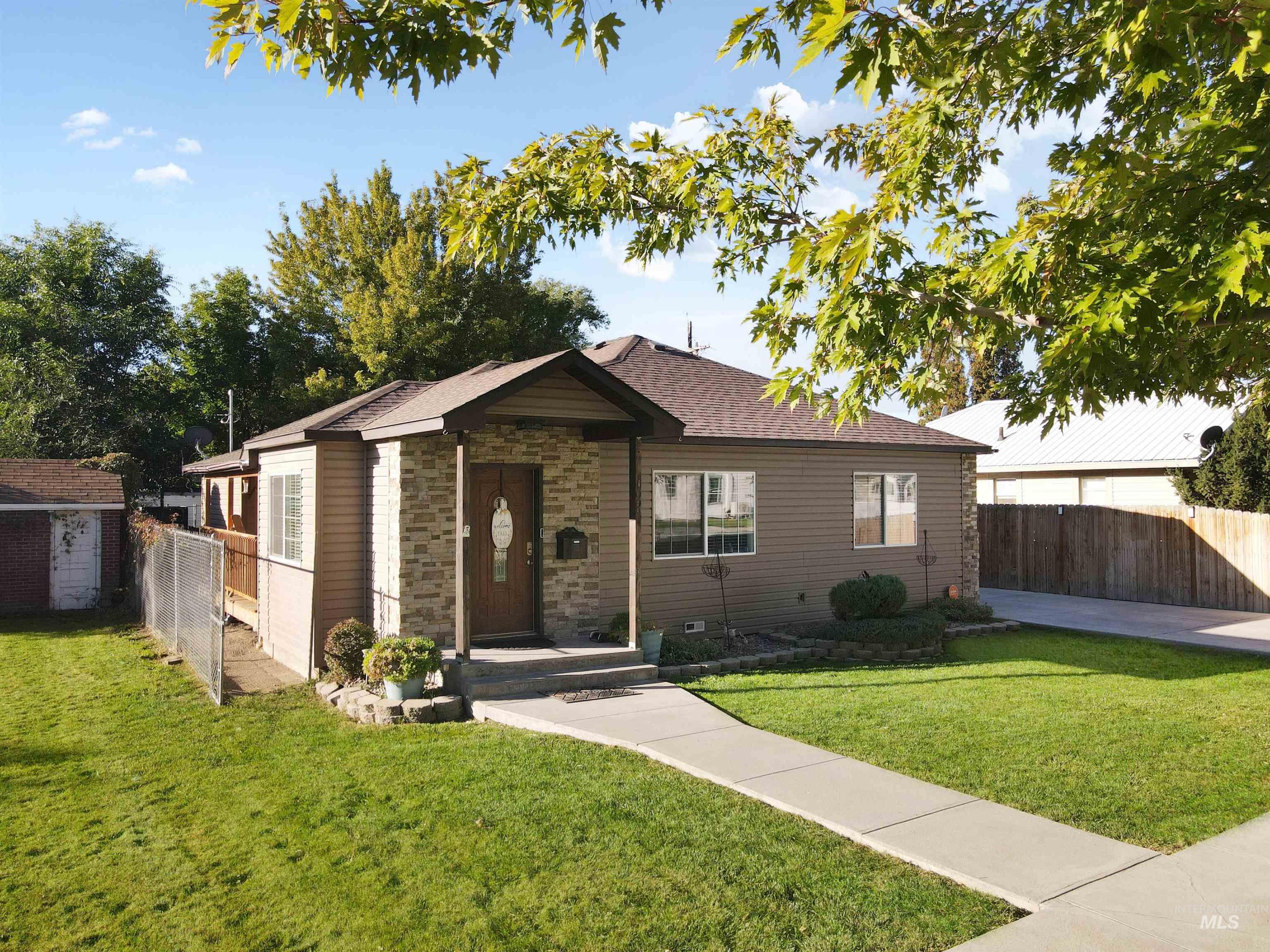 1009 9th Street Rupert, ID 83350 - Photo 1 of 28 Stone facade with siding accents, gabled roof, established lawn, concrete pathway, and a detached shed structure