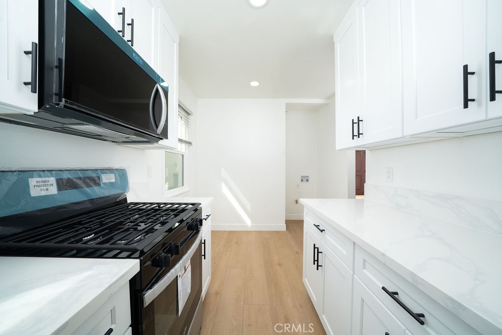 1046 Cedar Avenue Long Beach, CA 90813 - Photo 5 of 8 a kitchen with stainless steel appliances a sink dishwasher stove and microwave with wooden floor