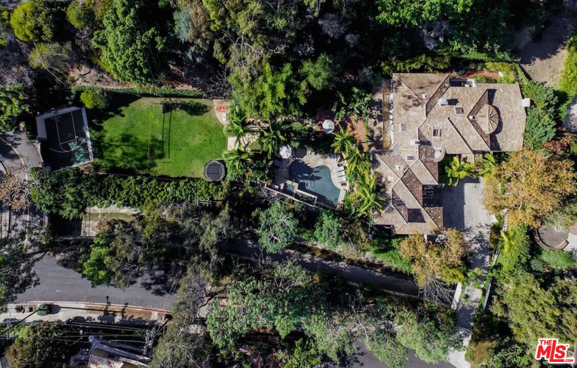 an aerial view of residential house with outdoor space and trees all around
