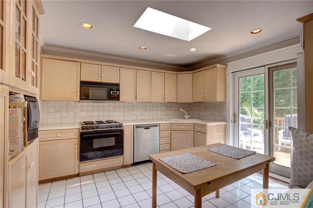 50 Wallace Road Middletown, NJ 07748 - Photo 8 of 24 a kitchen with stainless steel appliances granite countertop a stove top oven a sink dishwasher a dining table and chairs with wooden floor