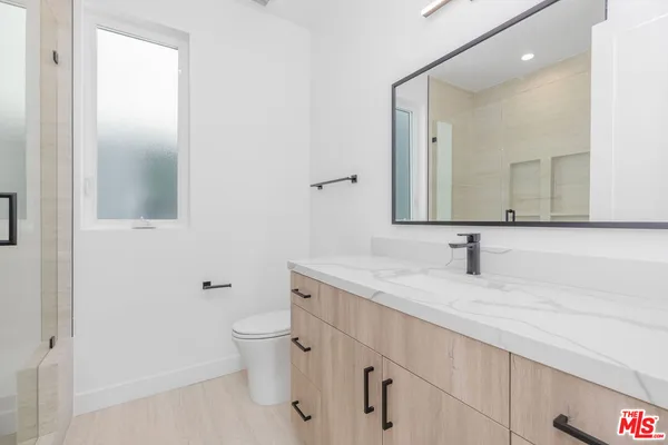 a bathroom with a granite countertop sink a toilet and a mirror