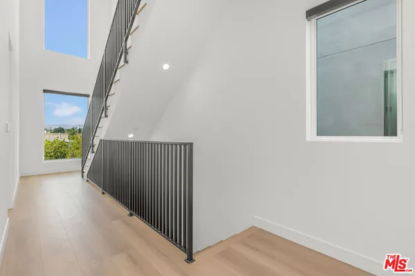 a view of a hallway to a room with wooden floor and windows