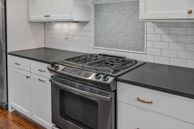 a kitchen with stainless steel appliances granite countertop a stove and a wooden floors