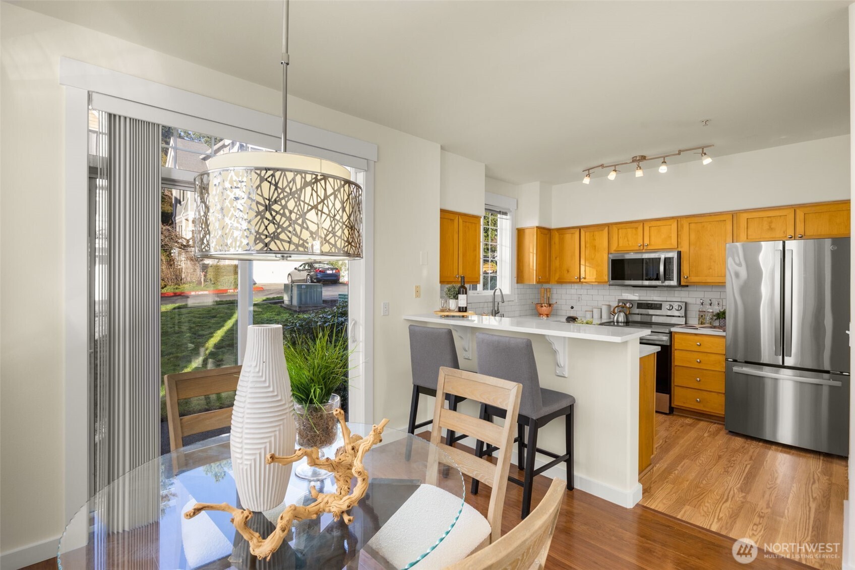 23120 Southeast Black Nugget Road, Unit C1 Issaquah, WA 98029 - Photo 8 of 31 a kitchen with stainless steel appliances granite countertop a refrigerator a sink dishwasher and a dining table with wooden floor