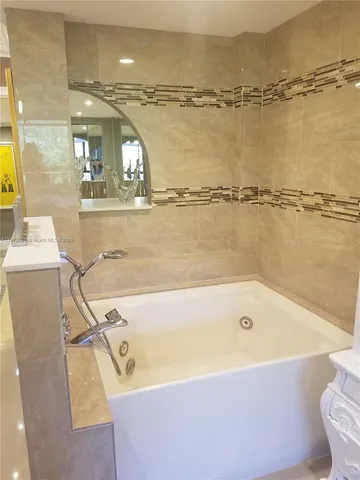 a bathroom with a tub a mirror and a shower