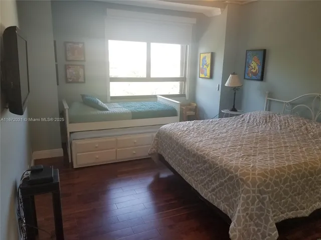 a bedroom with a bed and a flat tv screen on the dresser