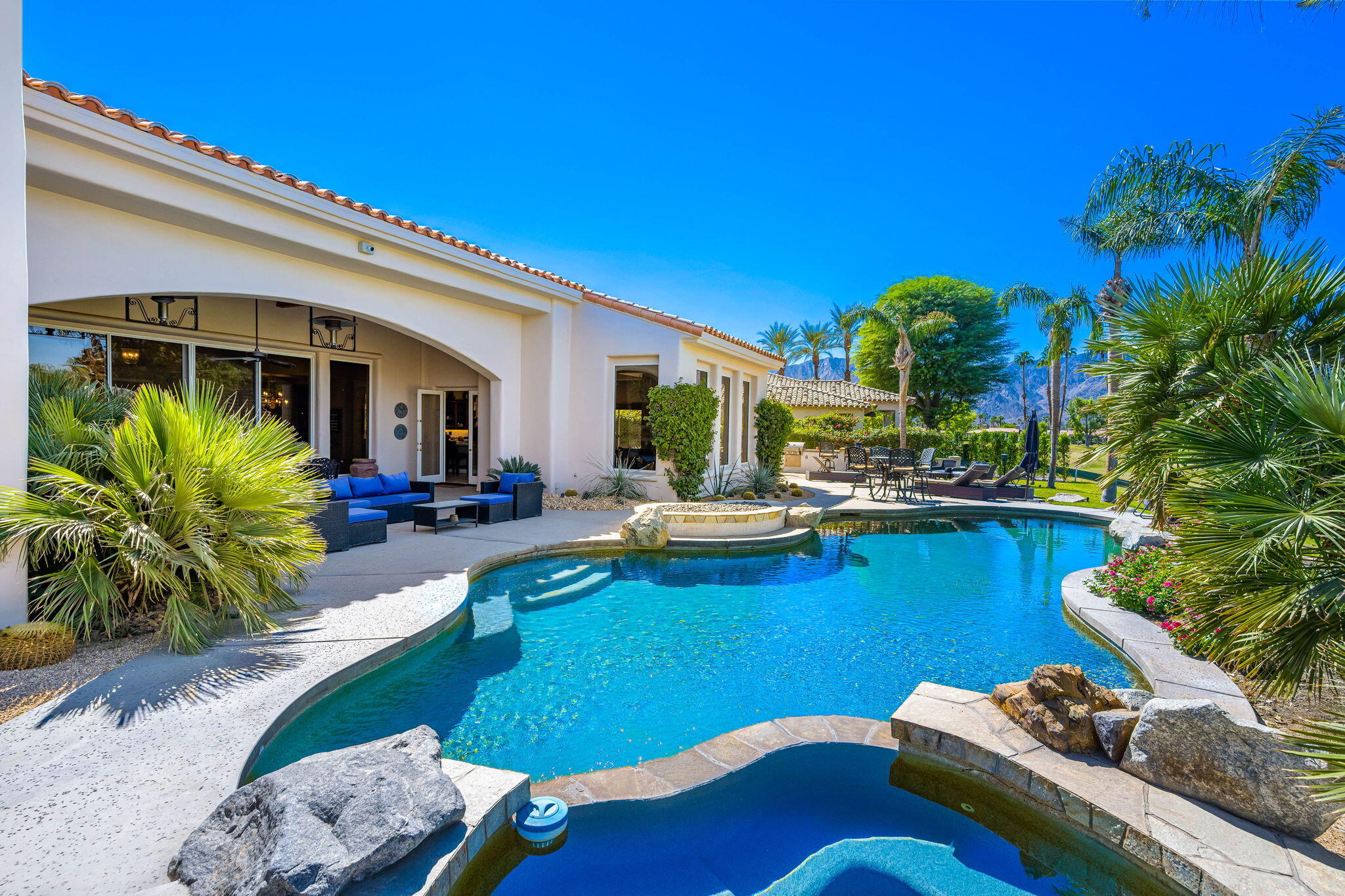 79290 Cetrino La Quinta, CA 92253 - Photo 43 of 74 a view of a patio with couches table and chairs under an umbrella with palm trees