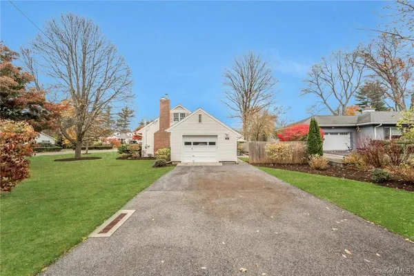 a view of white house with a yard and large tree