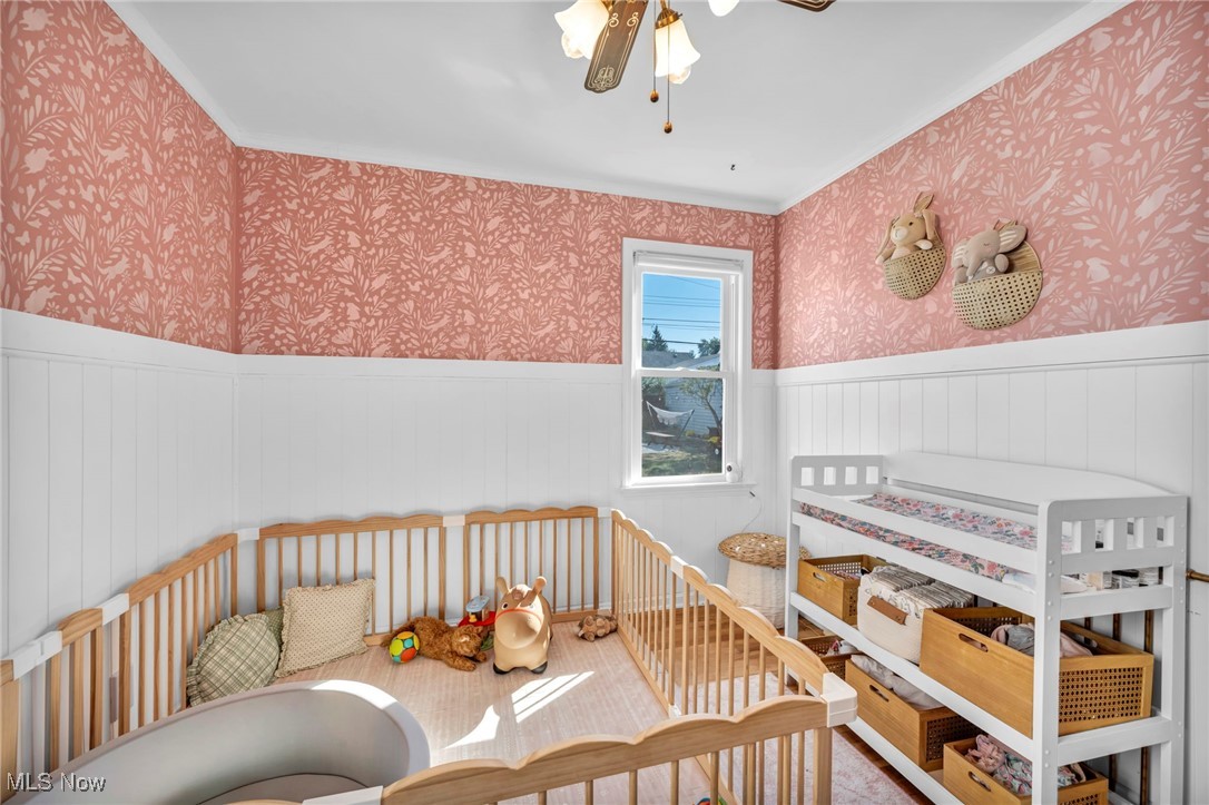 4607 Redfern Road Parma, OH 44134 - Photo 17 of 38 Bedroom featuring wallpapered walls, ceiling fan, wainscoting, crown molding, and a nursery area