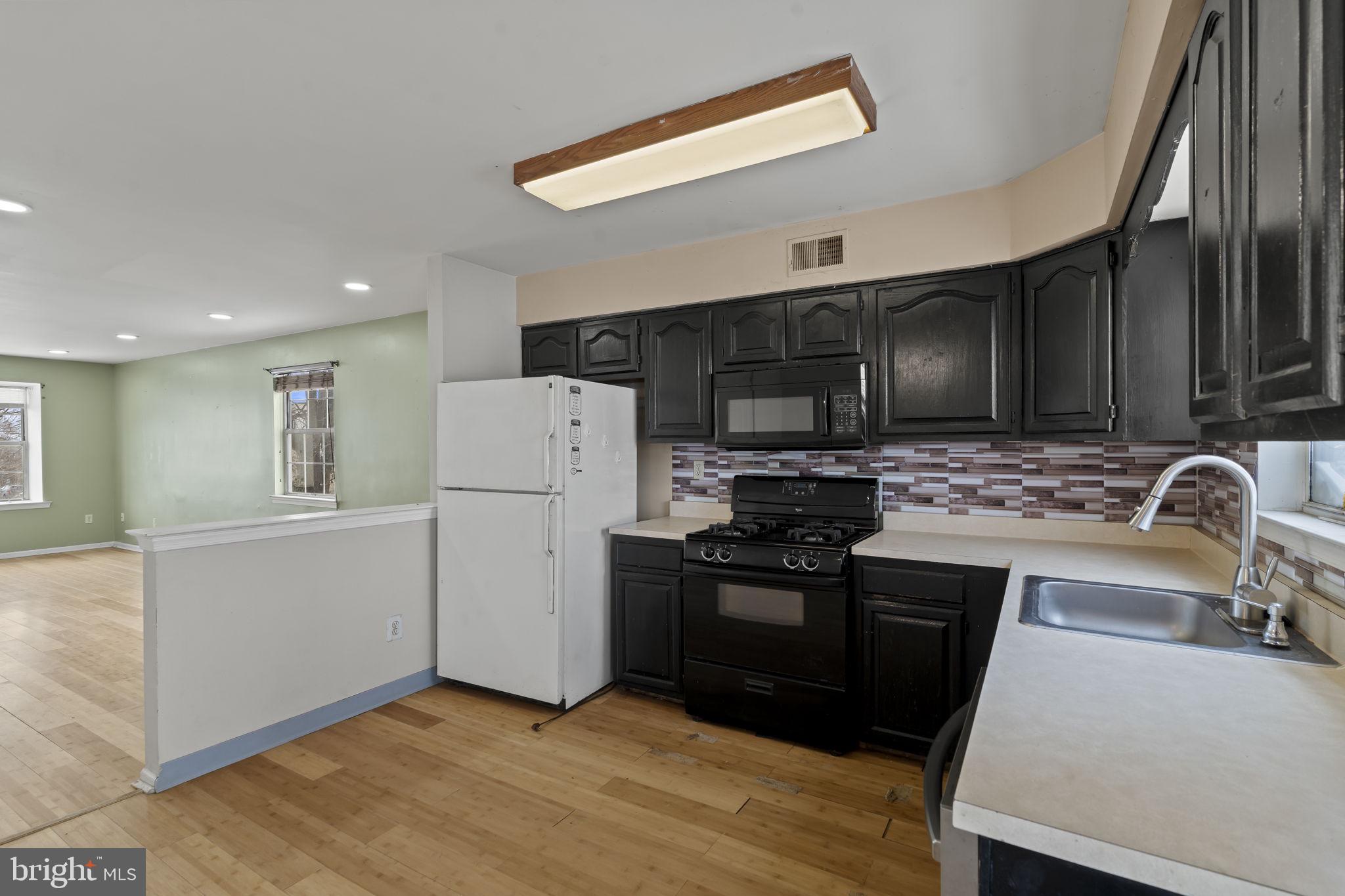 6500 Ditman Street Philadelphia, PA 19135 - Photo 11 of 30 a kitchen with granite countertop a stove a sink and a refrigerator