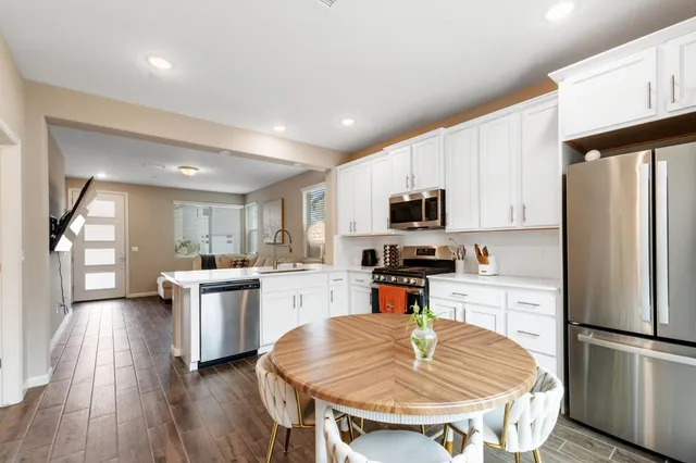 a kitchen with stainless steel appliances granite countertop a refrigerator a stove top oven a sink dishwasher and white cabinets with wooden floor