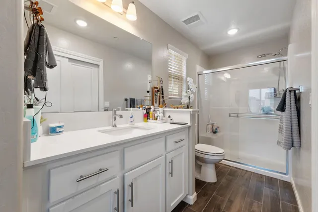 a bathroom with a sink a toilet a mirror and shower