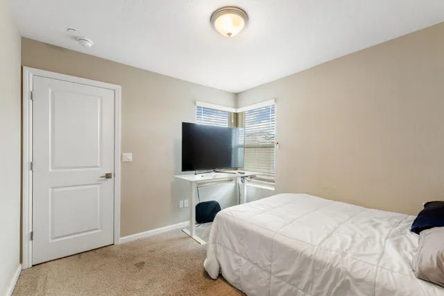 a bedroom with a bed and a flat tv screen on wall
