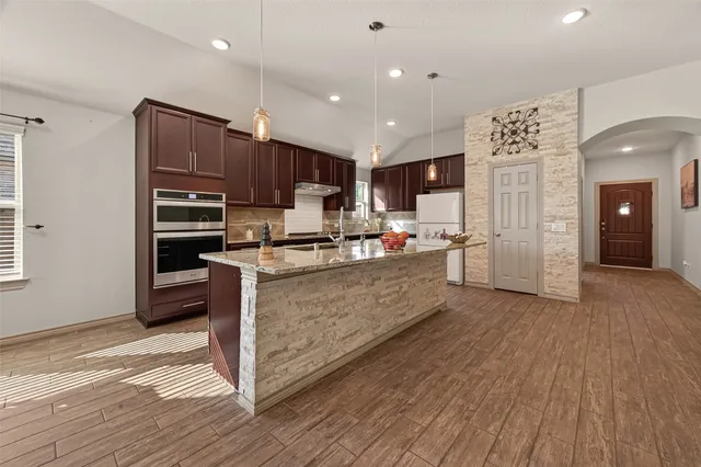 a kitchen with stainless steel appliances kitchen island granite countertop a refrigerator and a stove top oven
