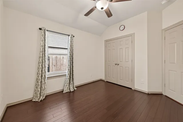 an empty room with wooden floor chandelier fan and windows