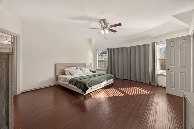 a spacious bedroom with a bed and wooden floor