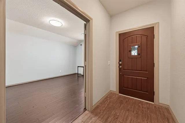 an empty room with wooden floor closet and windows
