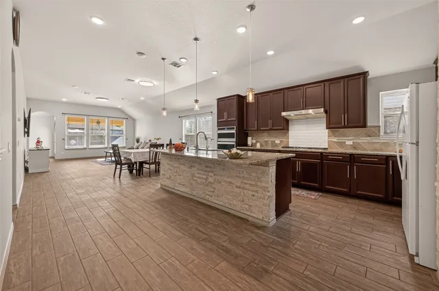 a kitchen with stainless steel appliances kitchen island granite countertop wooden floors a stove and a sink