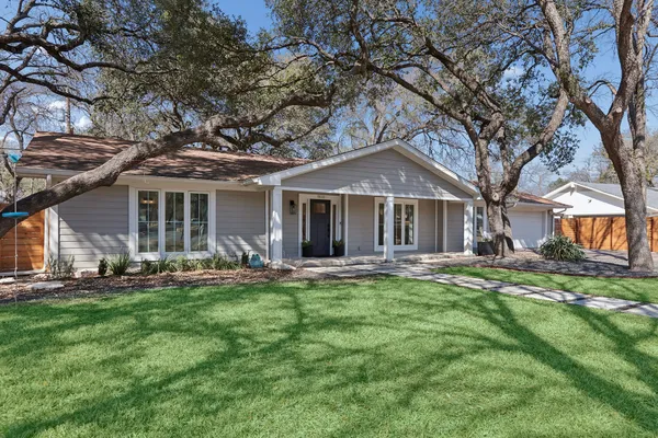 a front view of a house with a garden and trees