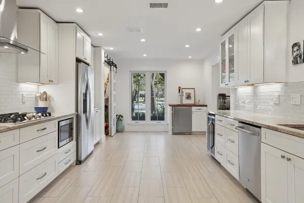 a large white kitchen with cabinets a sink and appliances