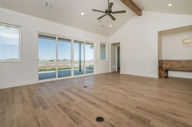 a view of an empty room with a window and wooden floor