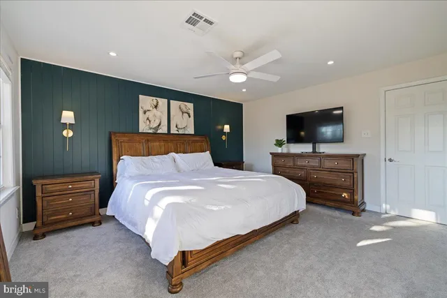 a bedroom with a bed and a flat tv screen on dresser