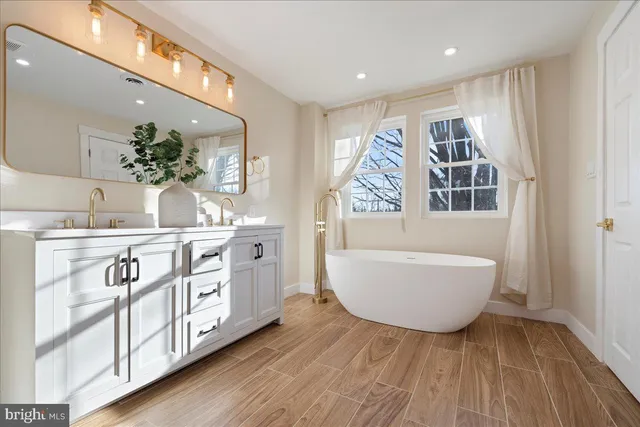 a spacious bathroom with a double vanity sink a mirror and a bathtub