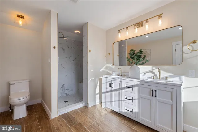a spacious bathroom with a double vanity sink a mirror and a toilet