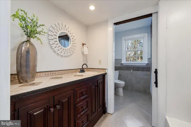 a bathroom with a granite countertop toilet sink and mirror