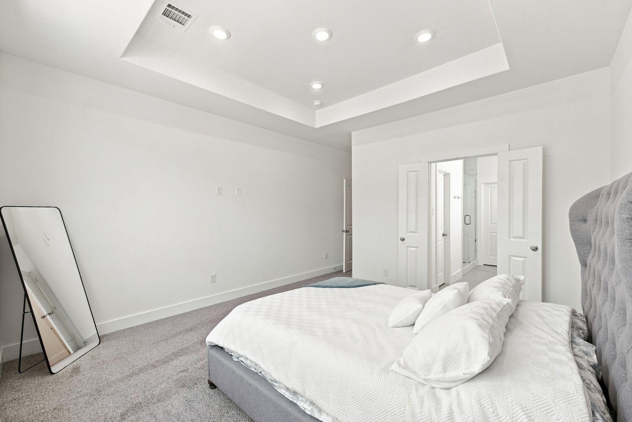 6063 Cebra Street Houston, TX 77091 - Photo 43 of 50 Primary suite offering generous space, a stylish tray ceiling with recessed lighting, and convenient direct access to the ensuite bathroom and walk-in closet. Photos are from a different property with the same floor plan, features, and finishes. **Orientation may vary.**
