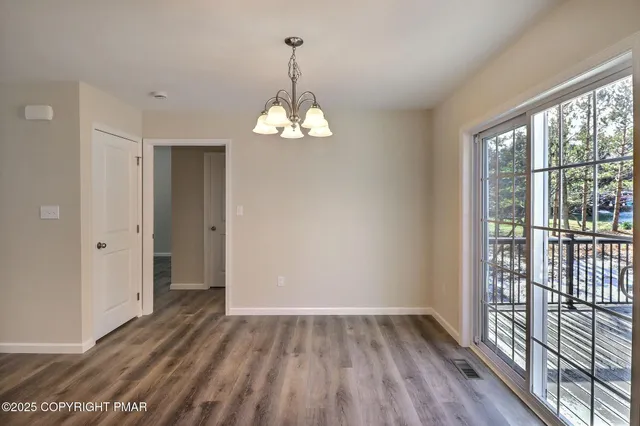 a view of an empty room with wooden floor and a ceiling fan