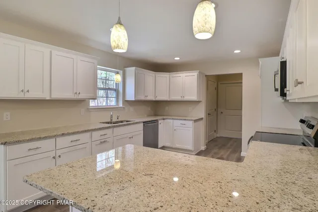 a view of an empty room with wooden floor and a ceiling fan
