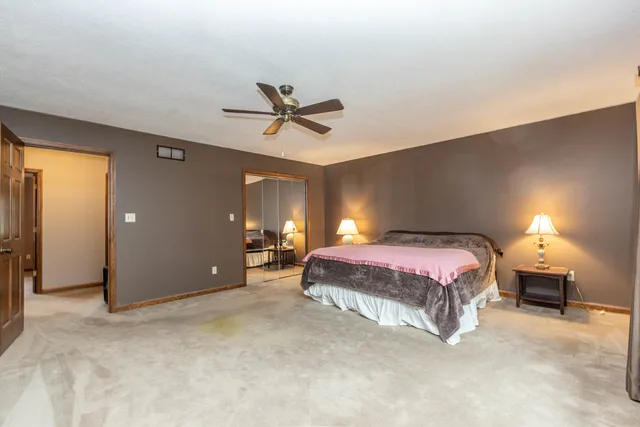 a spacious bedroom with a bed and a lamp