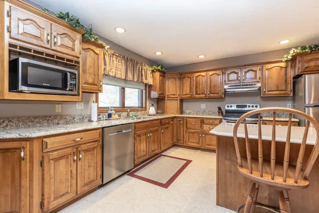 a kitchen with stainless steel appliances granite countertop a stove top oven a sink dishwasher and cabinets with wooden floor
