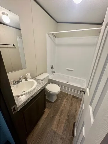 a bathroom with a granite countertop sink a toilet a tub and shower
