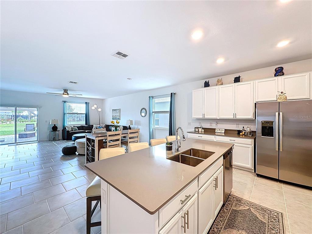 4190 Bull Street St. Cloud, FL 34772 - Photo 23 of 98 a kitchen with a refrigerator a stove a sink dishwasher a stove and a dining table with wooden floor
