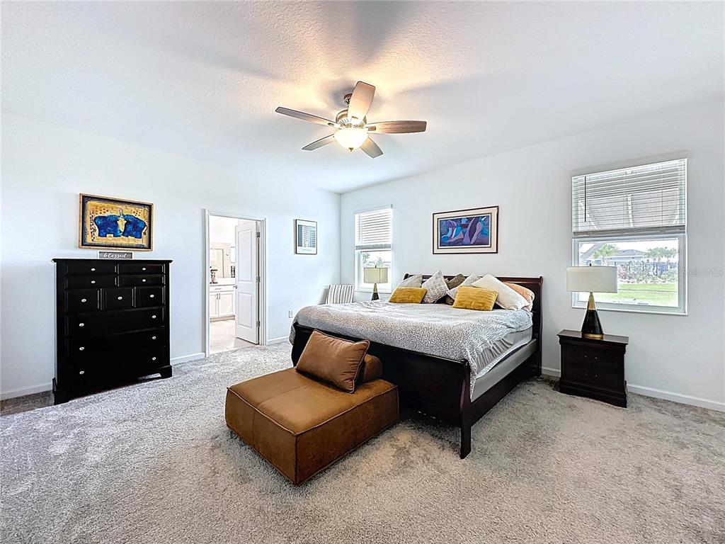 4190 Bull Street St. Cloud, FL 34772 - Photo 42 of 98 a spacious bedroom with a bed a dresser and a chandelier