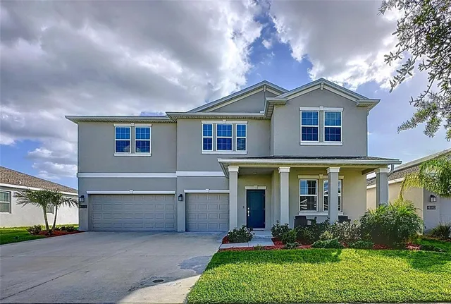 a front view of a house with a yard and potted plants