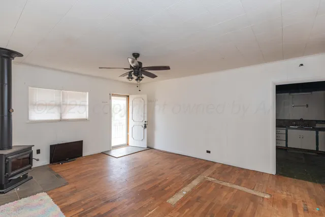 a view of an empty room with window and wooden floor