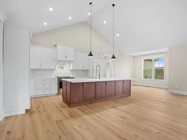 a large kitchen with a large counter top a sink stainless steel appliances and cabinets