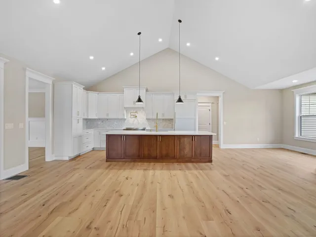a view of an empty room with kitchen and a window