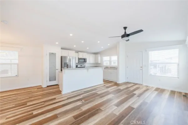 a view of kitchen and empty room with wooden floor and window