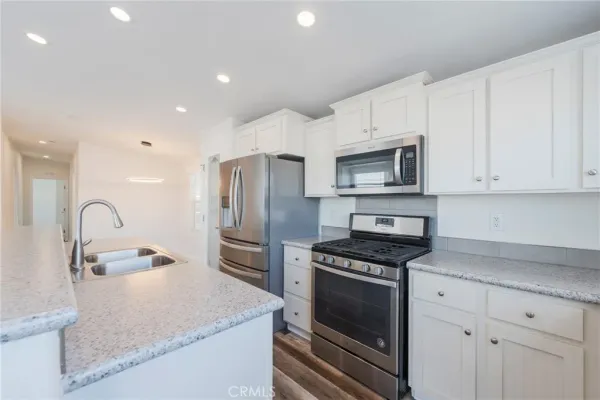 a kitchen with granite countertop white cabinets and stainless steel appliances