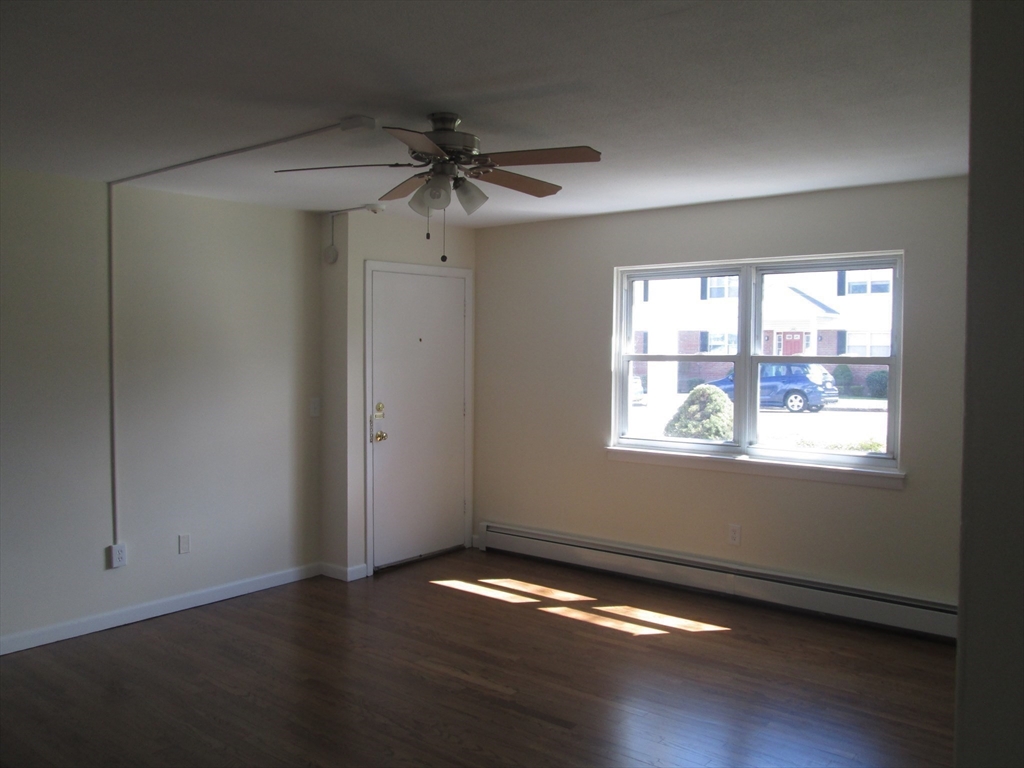 119 Colonial Circle, Unit B Chicopee, MA 01020 - Photo 5 of 17 an empty room with wooden floor fan and windows