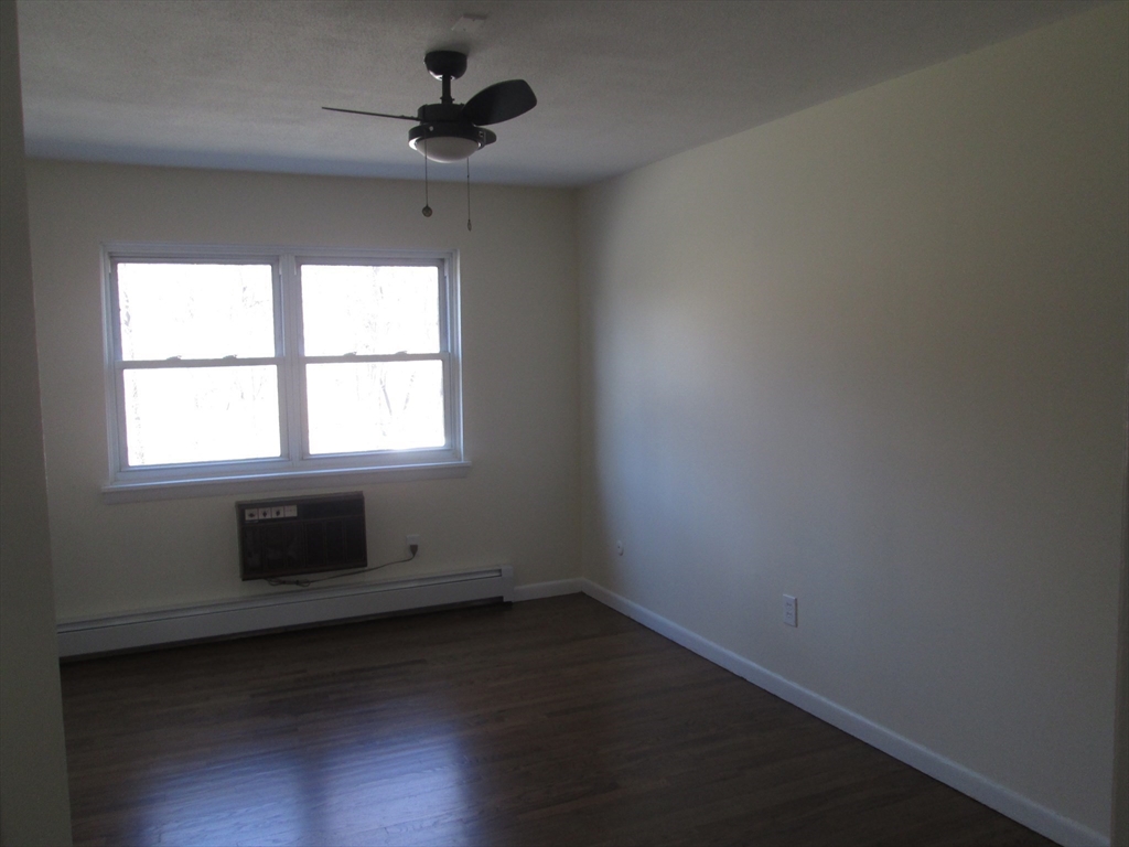 119 Colonial Circle, Unit B Chicopee, MA 01020 - Photo 9 of 17 an empty room with wooden floor and windows