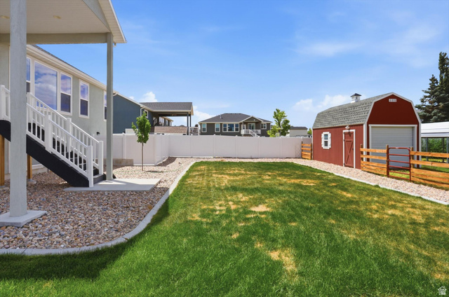3636 West 910 South Syracuse, UT 84075 - Photo 66 of 70 Expansive backyard featuring a manicured lawn, a detached red barn-style shed, and a white vinyl privacy fence