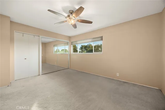 an empty room with windows and fan