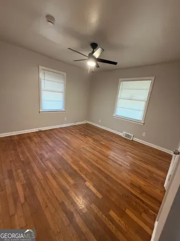 a view of an empty room with window and chandelier fan